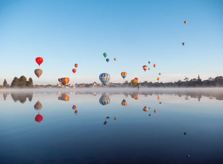Hot air balloons over the Waikato River with Hamilton in the background.